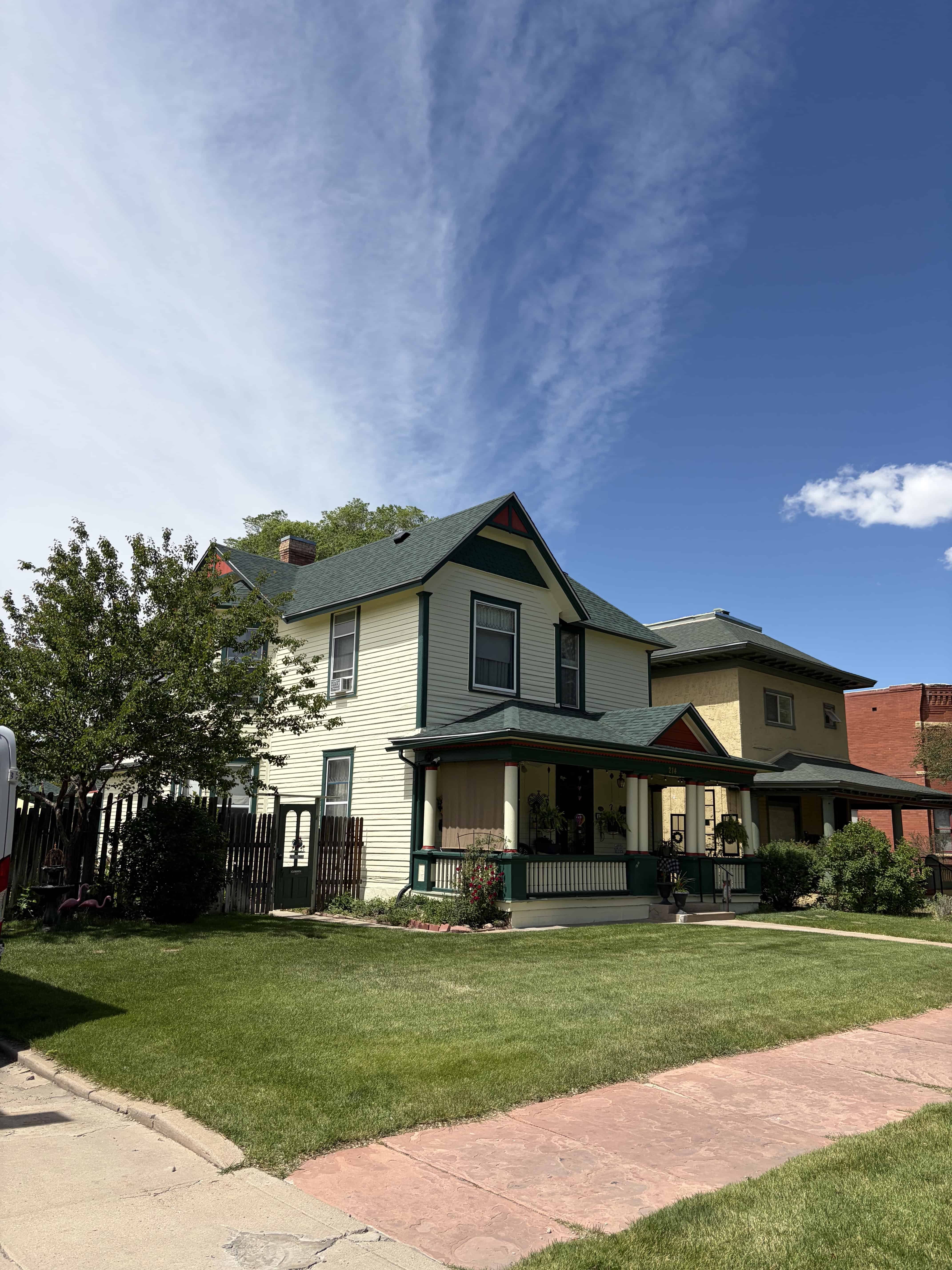 Victorian house with new roofing and well-maintained lawn.