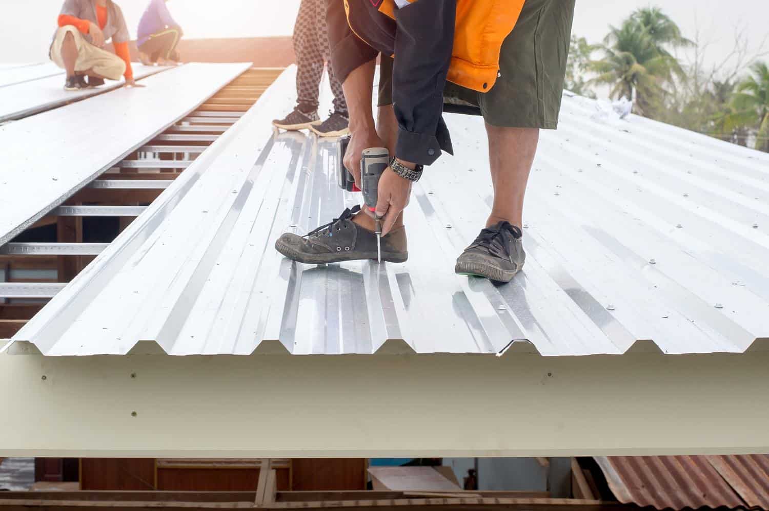 Roofers fastening metal panels on a commercial roof