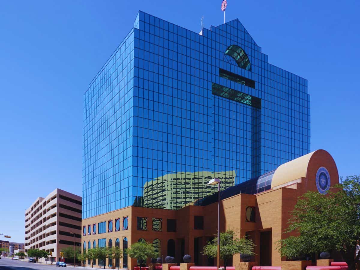 Modern glass office building with reflective blue windows and surrounding cityscape.