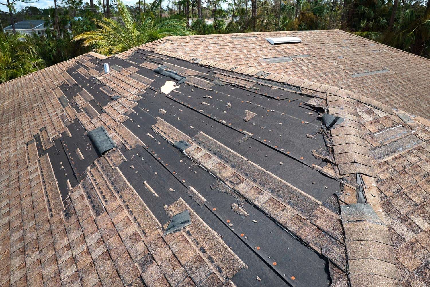 Damaged roof with missing shingles and exposed underlayment in Highlands Ranch, CO.