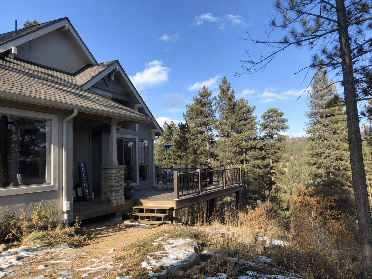 House with new roof and deck in a wooded area during fall.